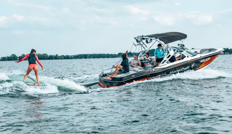Žena surfující za lodí při wakesurfingu